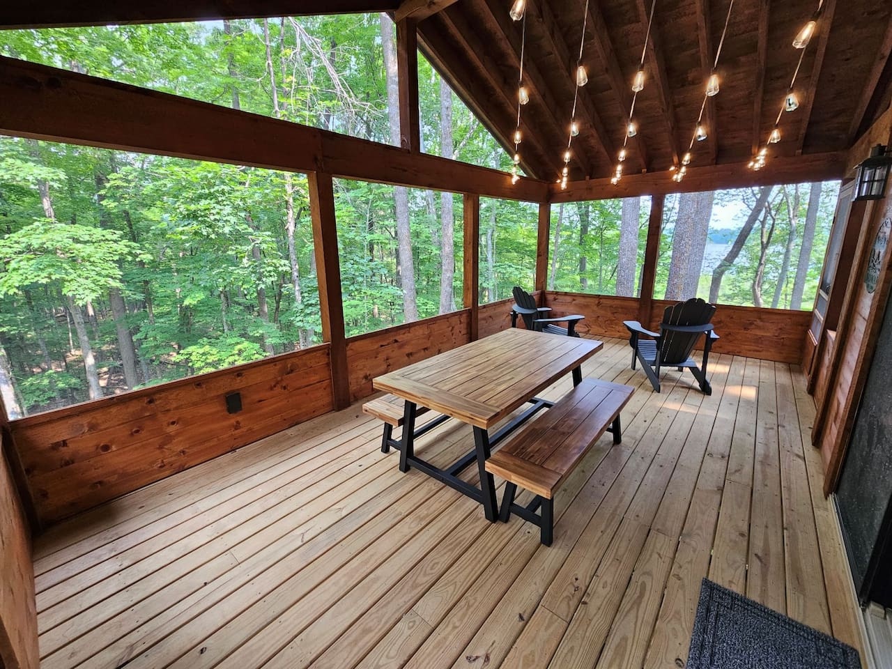 Your screened porch offers peaceful forest dining with twinkling lights overhead and panoramic woodland views through floor-to-ceiling windows.