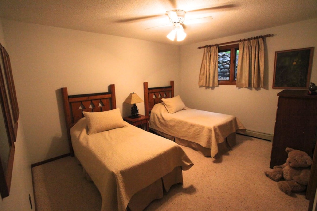Unwind in this cozy twin bedroom where warm lighting and rustic wooden headboards create a peaceful retreat for your mountain getaway.