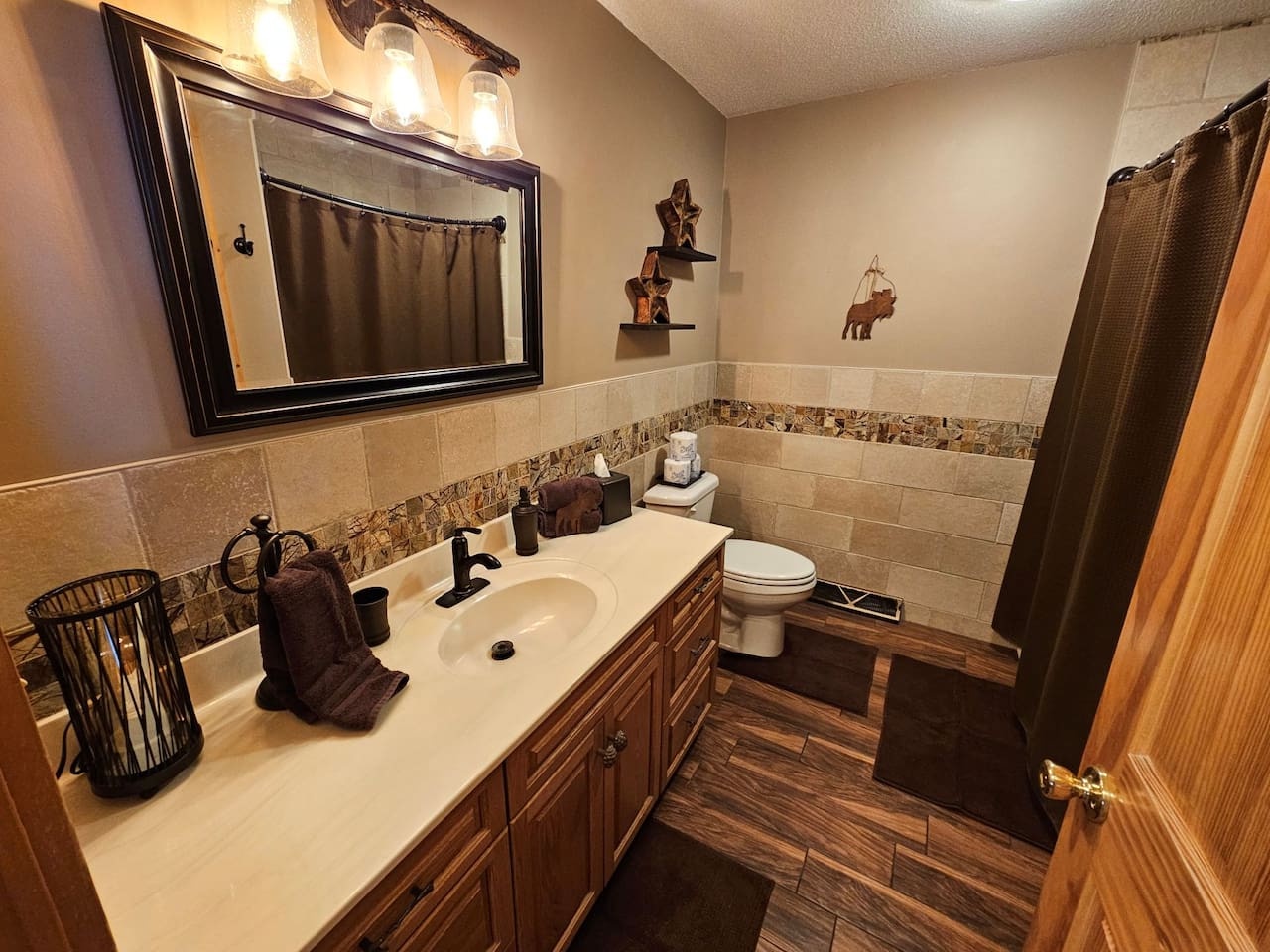 Refresh in this beautifully styled bathroom with rustic charm, featuring warm wood-look flooring, elegant tile work, and thoughtful western touches.