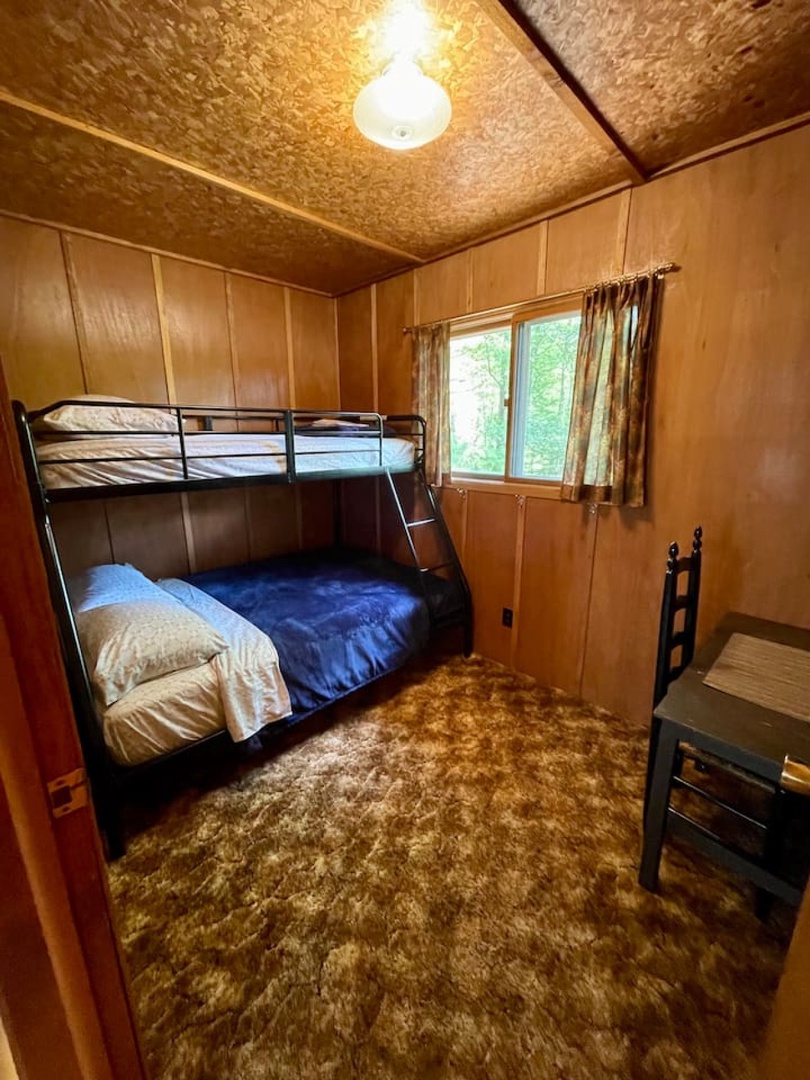 Cozy cabin bedroom with sturdy bunk beds perfect for kids or groups, featuring warm wood paneling and peaceful forest views.