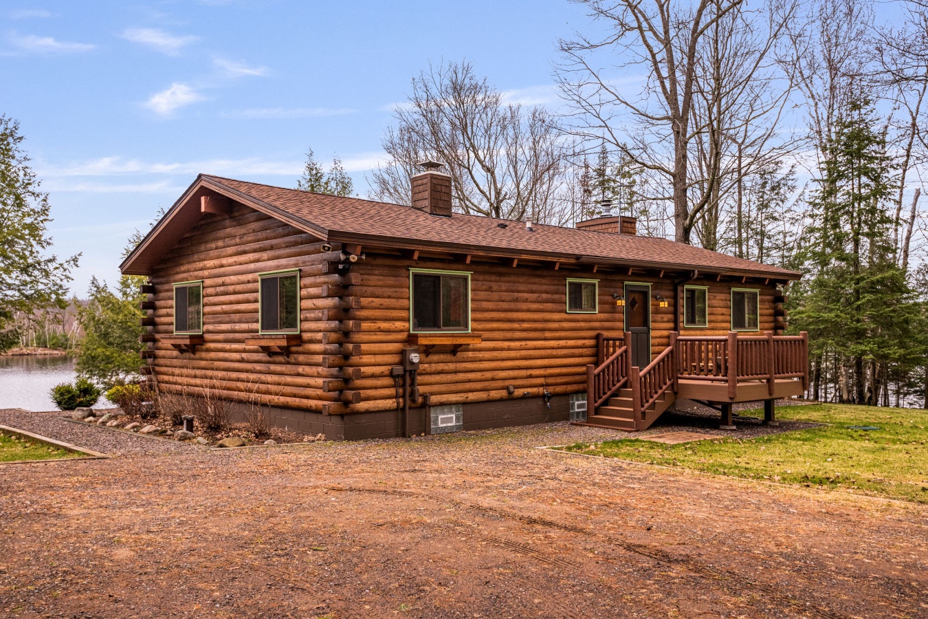 This charming log cabin sits peacefully beside a pristine lake, surrounded by towering trees and natural beauty.