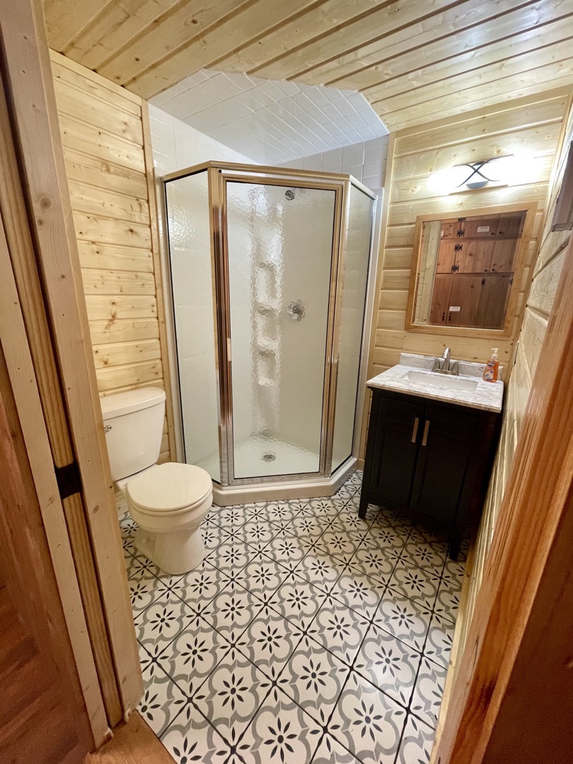 Step into your beautifully crafted bathroom with rustic wood walls, geometric tile floors, and modern fixtures creating the perfect retreat.