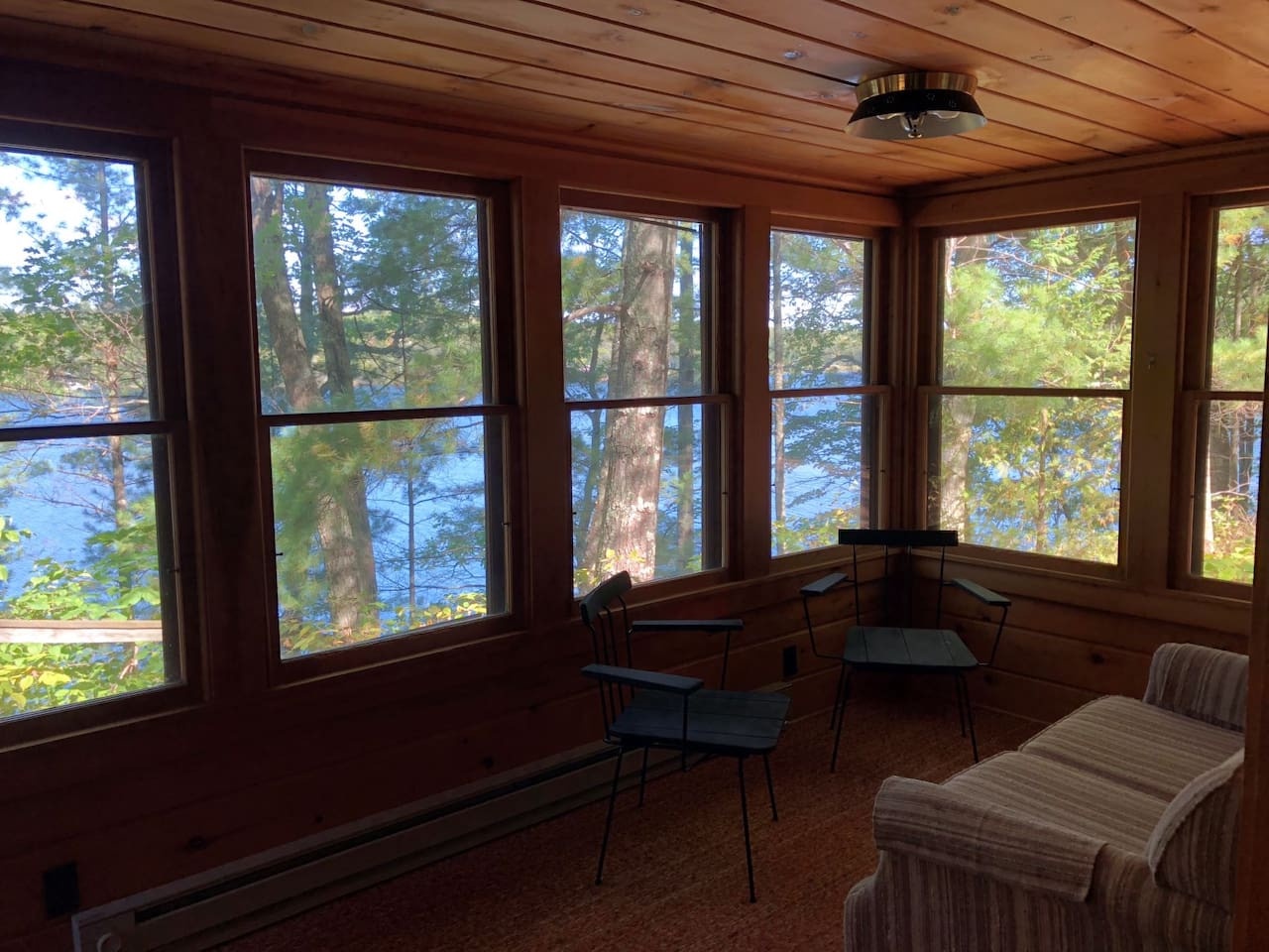 Cozy wood-lined room with panoramic lake views where you can relax and watch nature unfold through floor-to-ceiling windows.