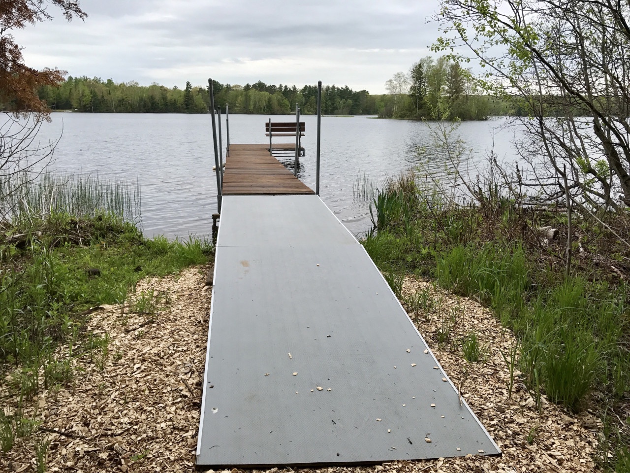 A private dock extends into pristine lake waters, surrounded by lush forest and natural shoreline.