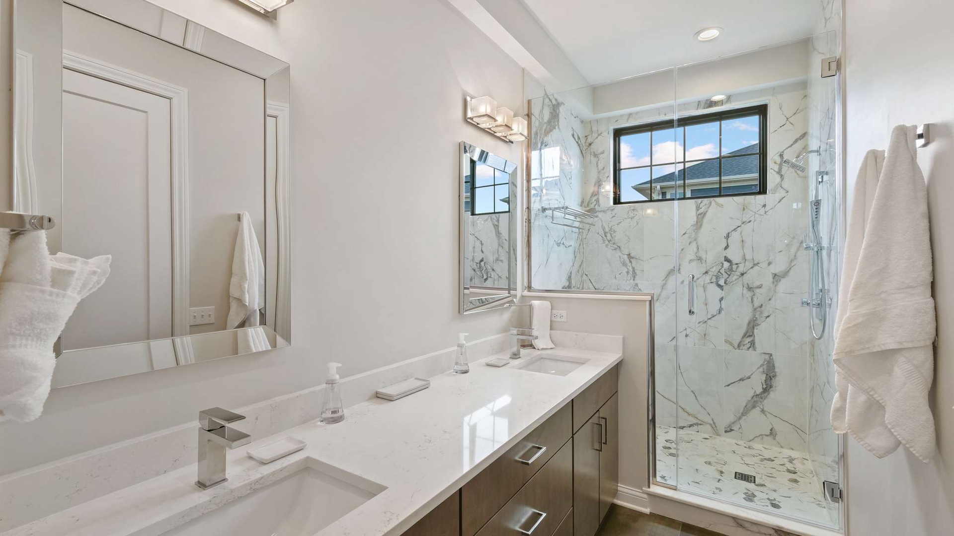 Indulge in your private marble oasis with a spacious glass shower and elegant double vanity—luxury awaits your every moment.