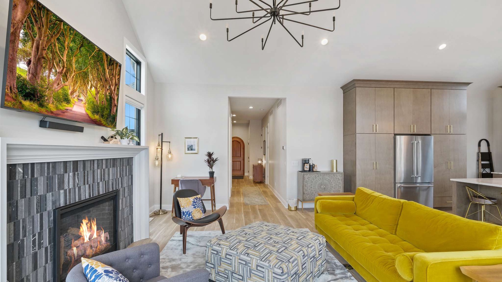 Relax in your stylish open-plan living space with a cozy fireplace, vibrant yellow sofa, and modern kitchen.