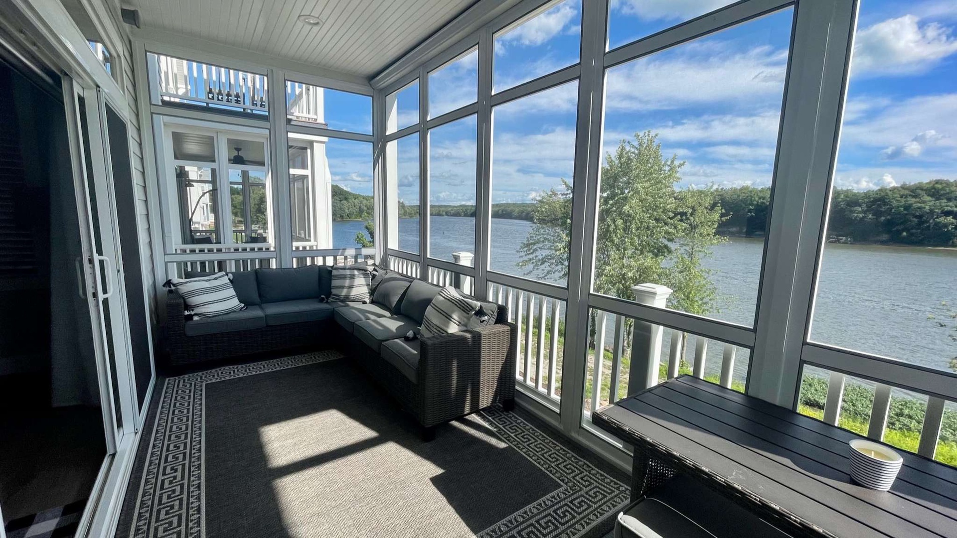 Relax in your glass-enclosed sunroom with panoramic lake views, comfortable seating, and peaceful waters just beyond your windows.