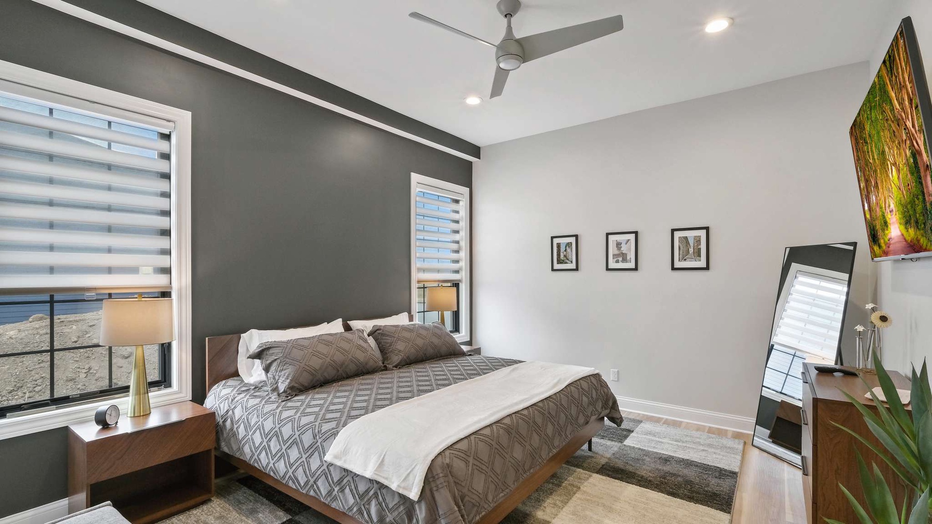 Relax in your modern bedroom featuring a plush king bed, designer furnishings, and a wall-mounted TV for ultimate comfort.