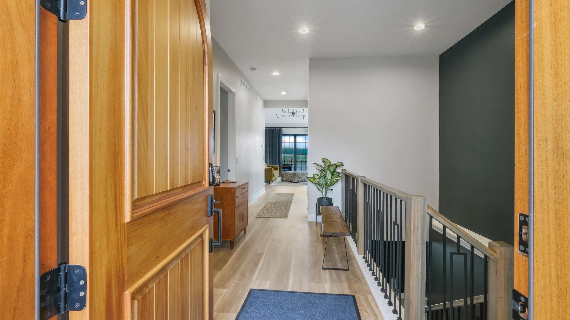 Step into your bright, modern hallway with warm wood accents and stylish green walls—your home away from home awaits.
