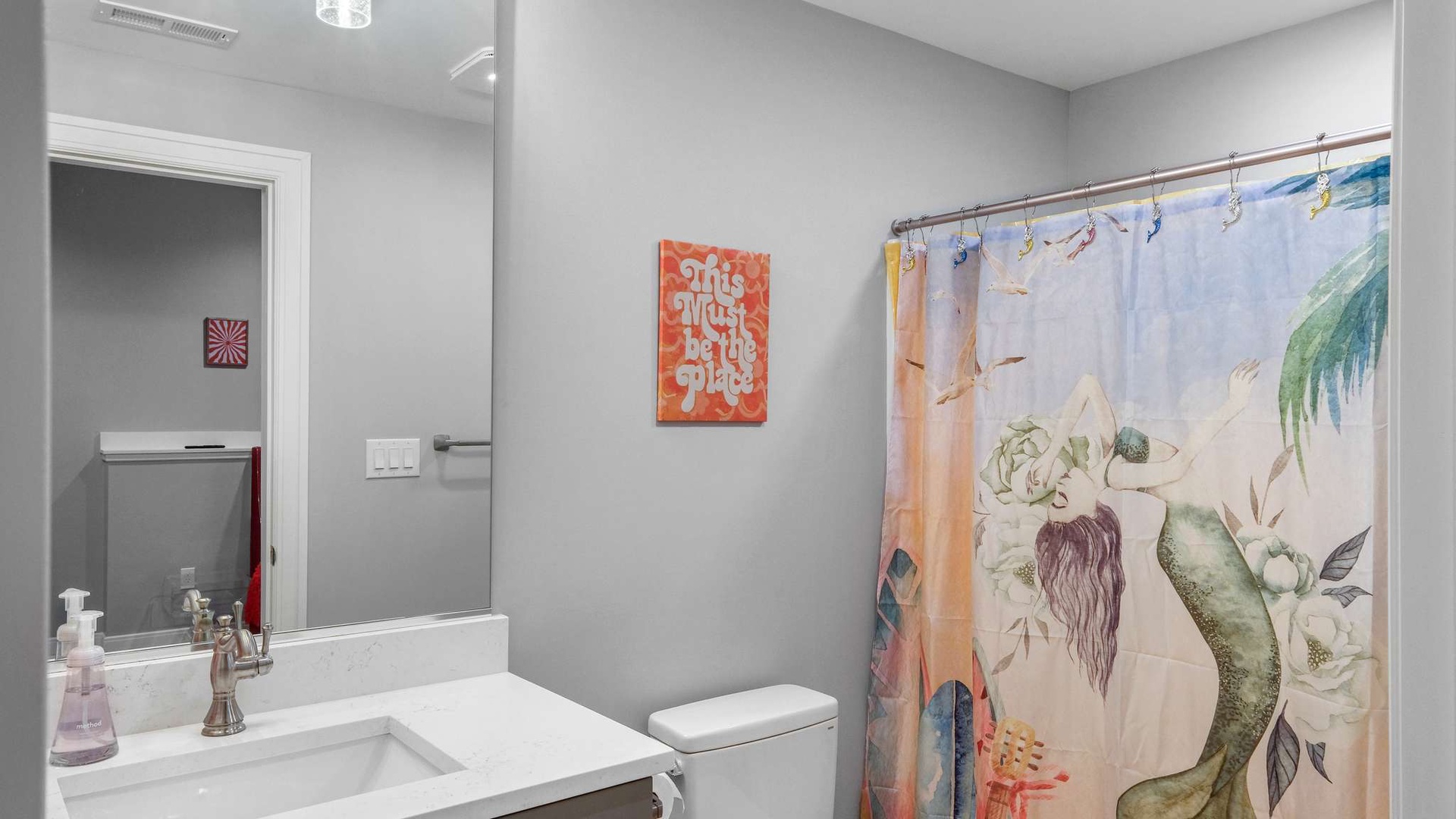 Refresh in your stylish bathroom featuring a walk-in shower with vibrant tropical curtain and modern fixtures.
