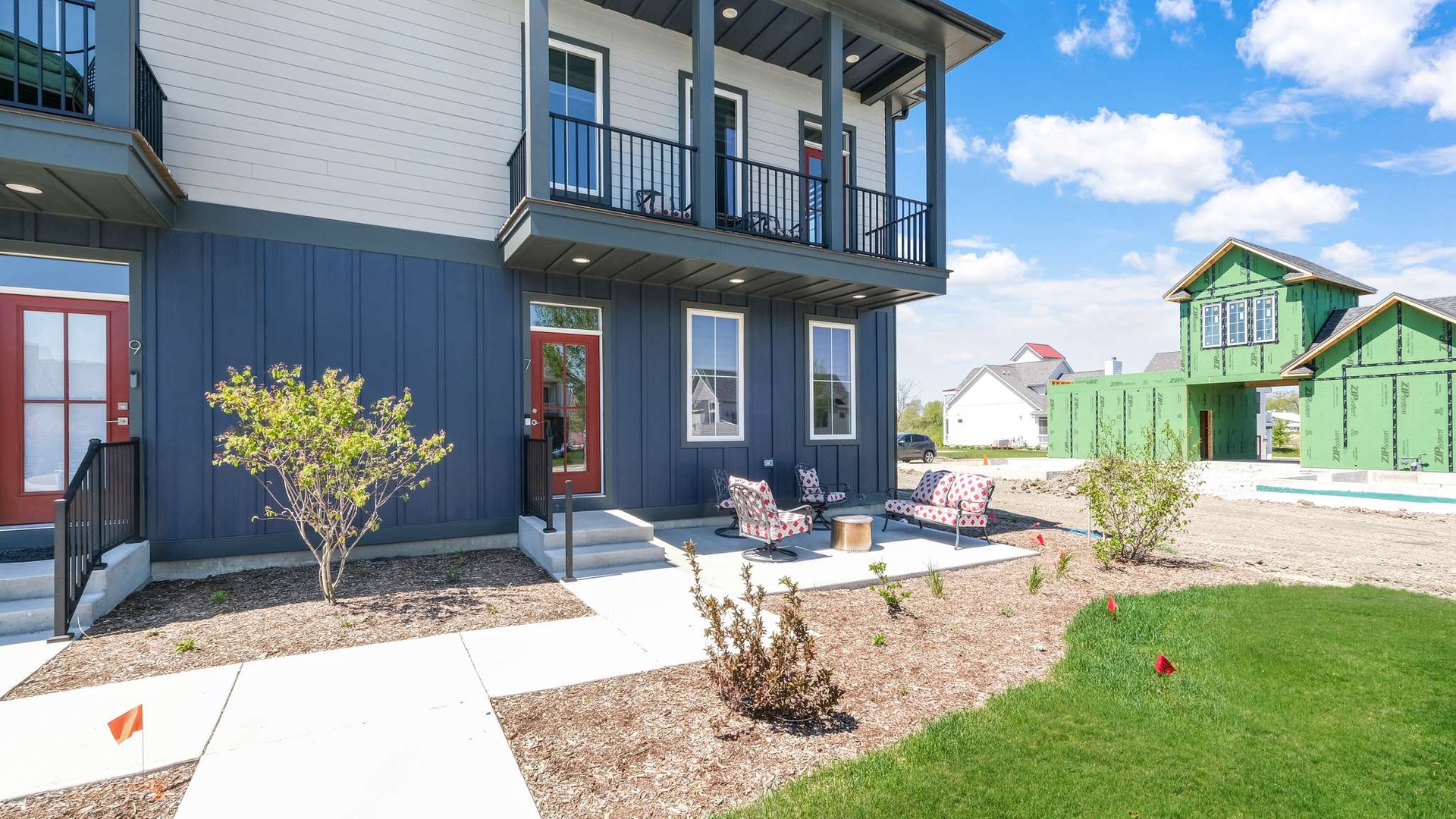 Modern two-story home with covered patio and outdoor seating in a developing neighborhood.