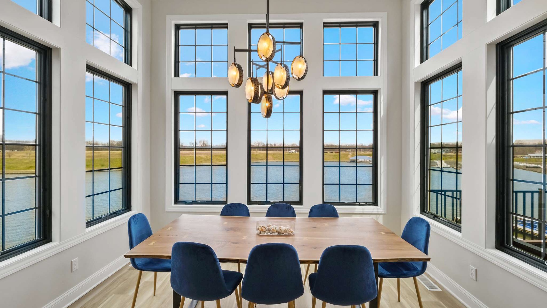 Gather around this stunning dining table surrounded by floor-to-ceiling windows showcasing beautiful water views.