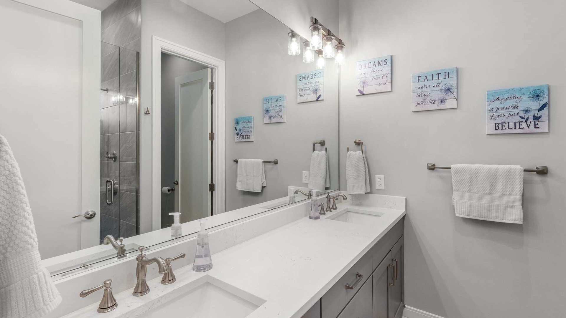 Your modern bathroom features dual vanities with marble countertops, plush towels, and inspiring coastal artwork to start your day refreshed.