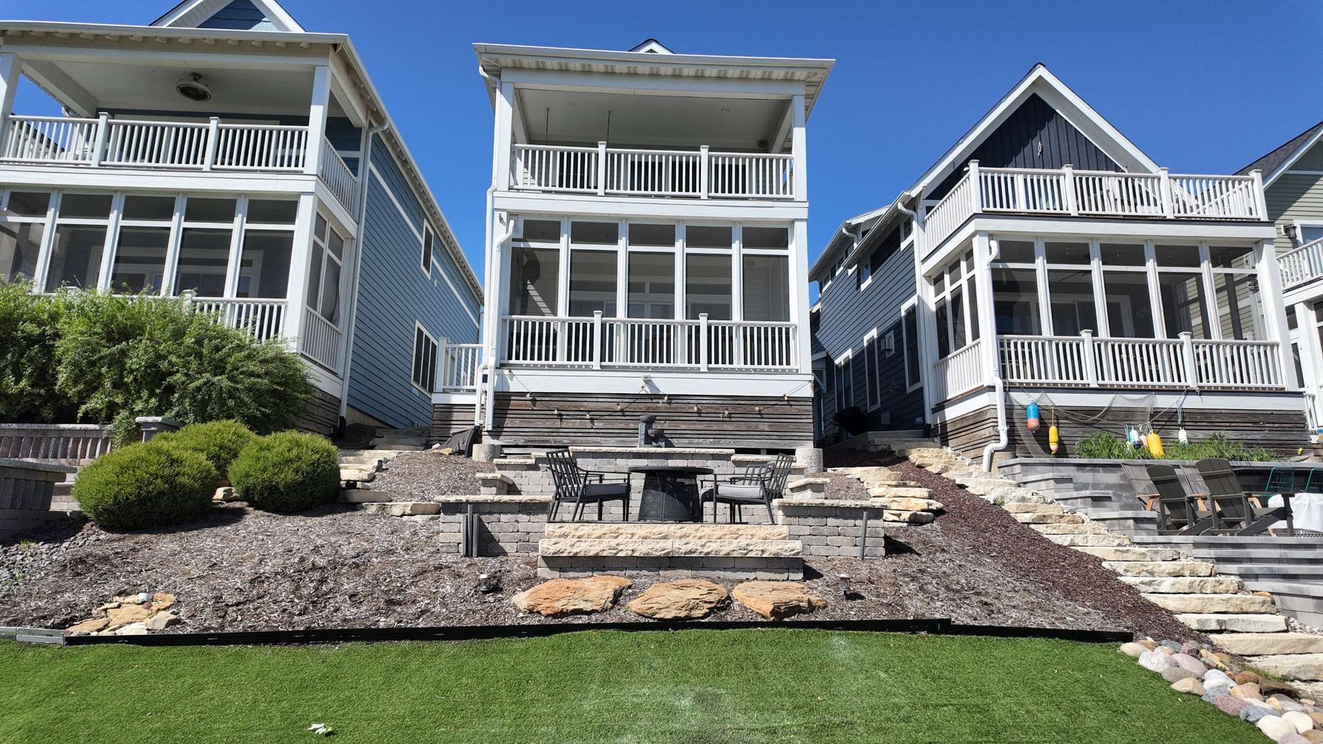 Charming beachside homes with multiple balconies and outdoor spaces, nestled in a picturesque coastal neighborhood under clear blue skies.