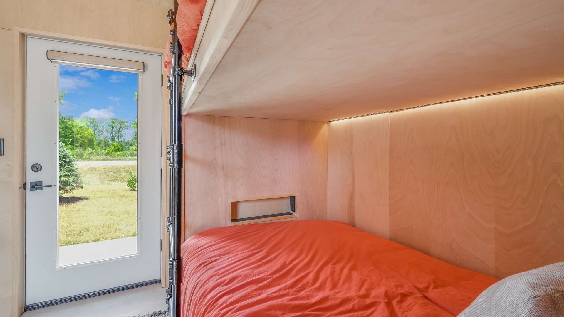 Wake up to peaceful garden views in your cozy bedroom, where warm wood tones and direct outdoor access create a serene retreat.