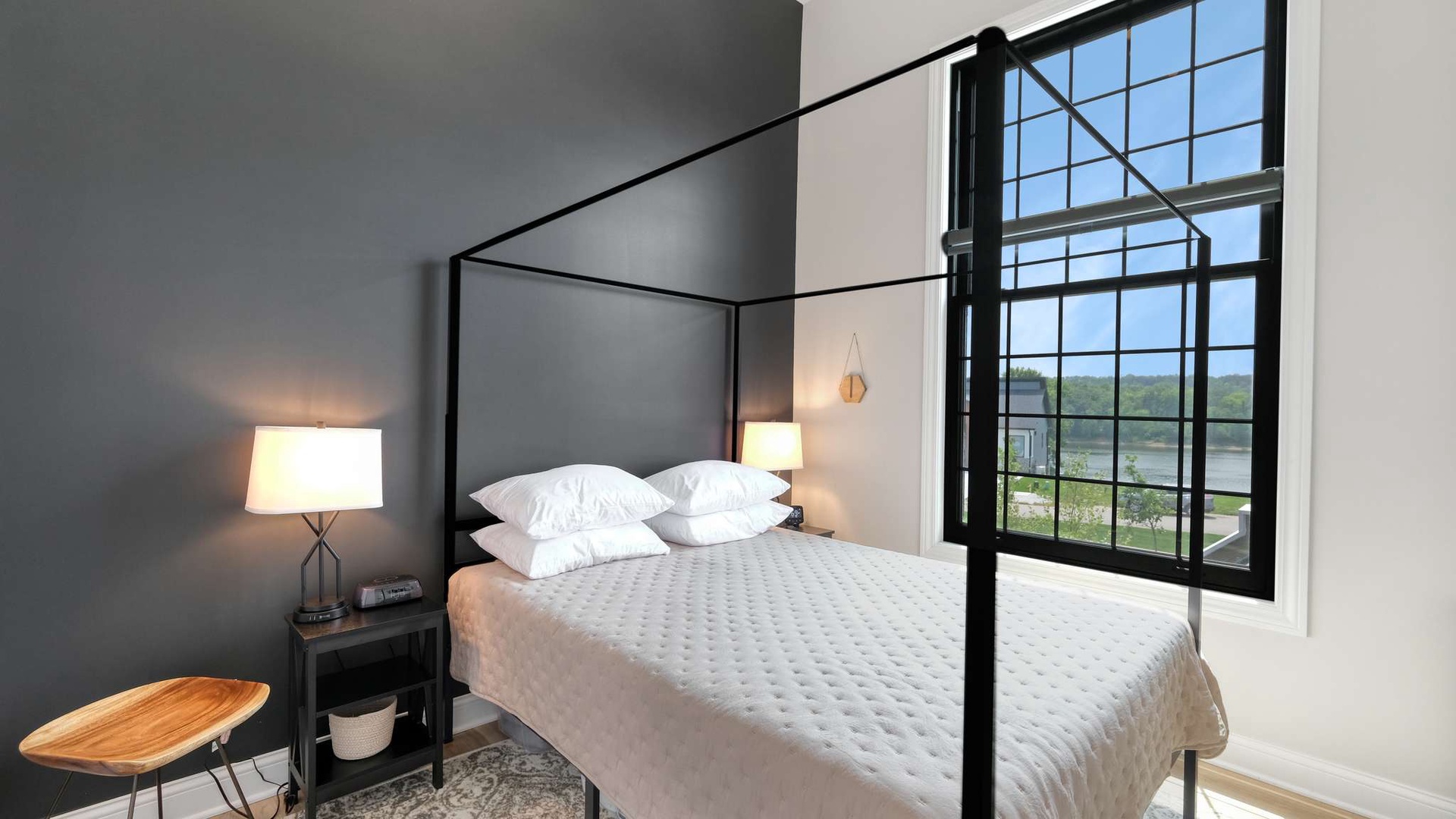 Drift off peacefully in this elegant four-poster bed with crisp white linens, surrounded by warm lighting and stunning lake views.