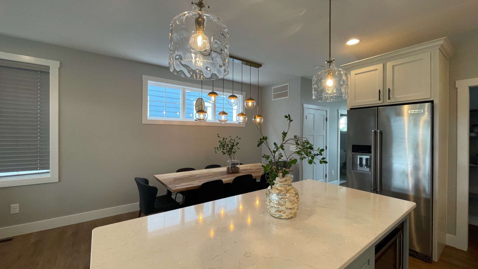 You'll love preparing meals in this bright, modern kitchen with sleek marble counters, statement lighting, and dining space.