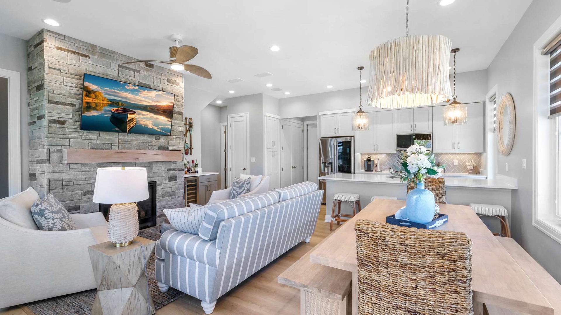 Unwind in your elegant living space featuring a cozy stone fireplace, stylish furnishings, and seamless flow to the modern kitchen.