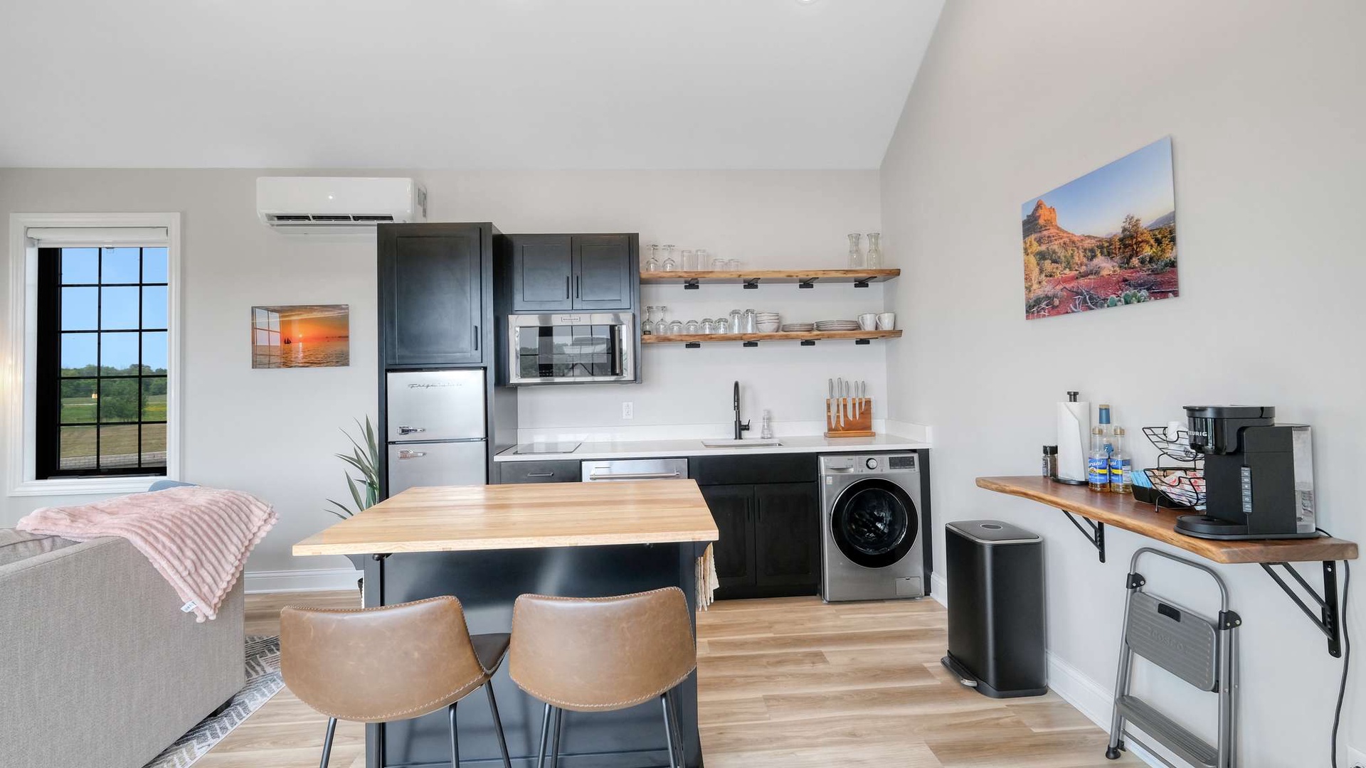 Your modern kitchen features sleek navy cabinets, butcher block counters, and everything you need including a washer for convenience.
