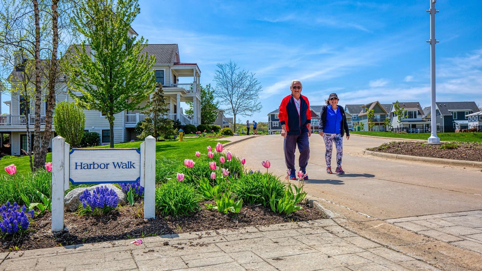Harbor Walk neighborhood entrance with spring blooms and residential homes creates a welcoming coastal community atmosphere.