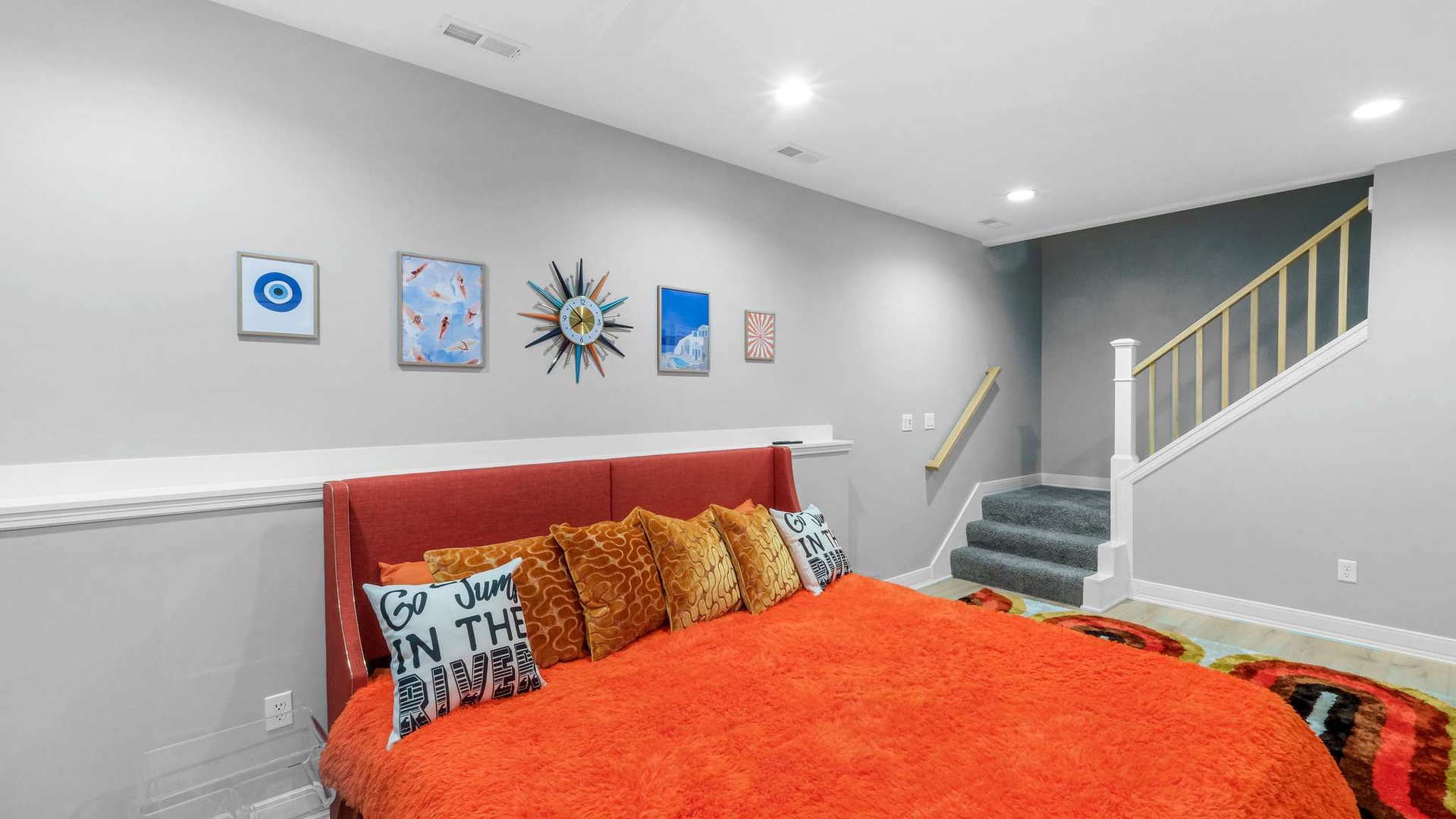 Cozy basement bedroom with vibrant orange bedding and playful wall art creates your perfect retreat space.
