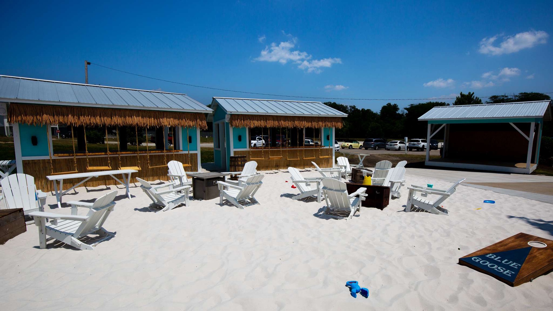 Beachfront cabanas with turquoise accents and white sand create a tropical resort atmosphere with lounge chairs for relaxation.