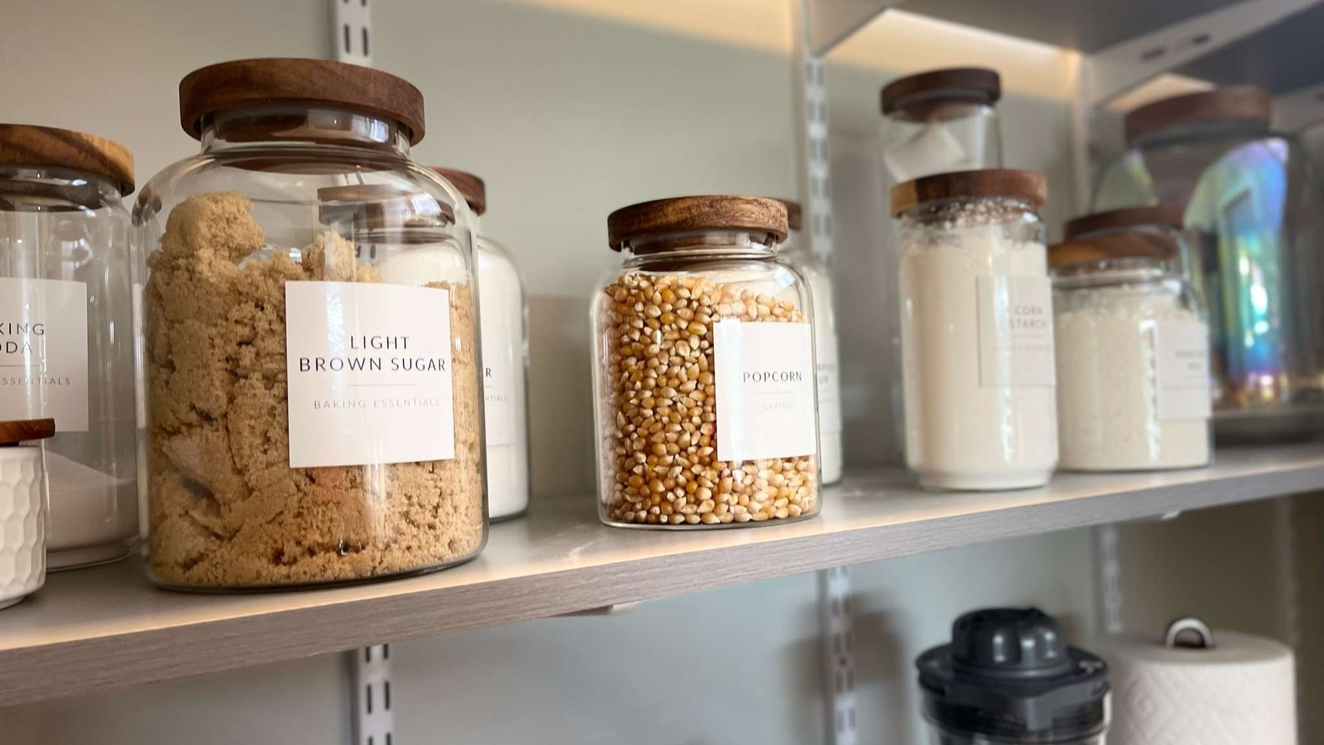 Stock your pantry with ease using these perfectly organized glass containers filled with baking essentials and popcorn kernels.