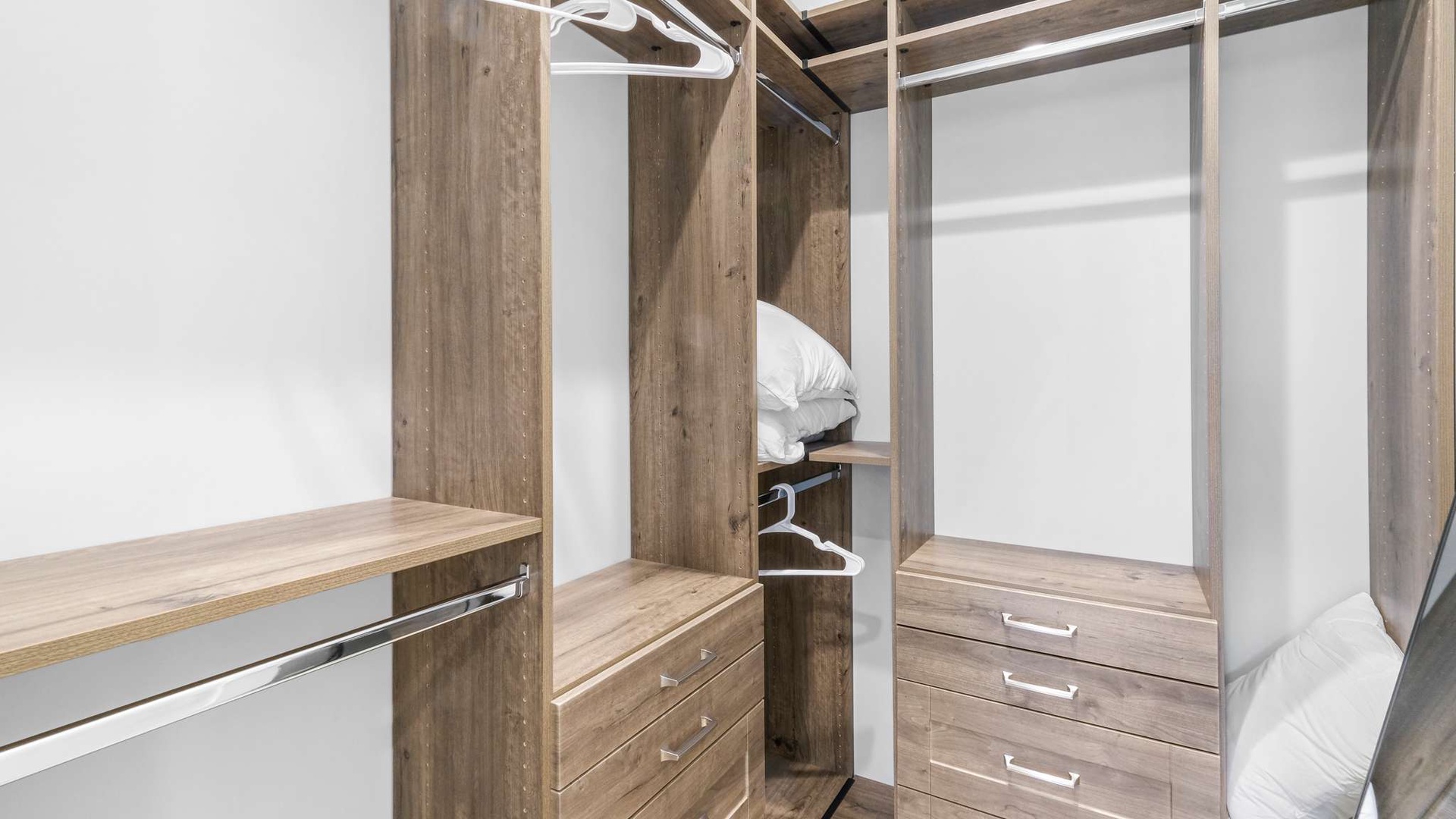 Your spacious walk-in closet features warm wood finishes, ample hanging space, and built-in drawers to keep your belongings perfectly organized.