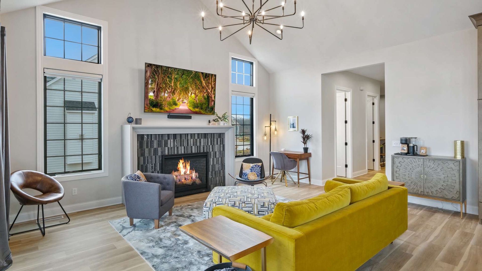 Unwind in your bright living space featuring a cozy fireplace, modern furnishings, and stunning natural light from oversized windows.