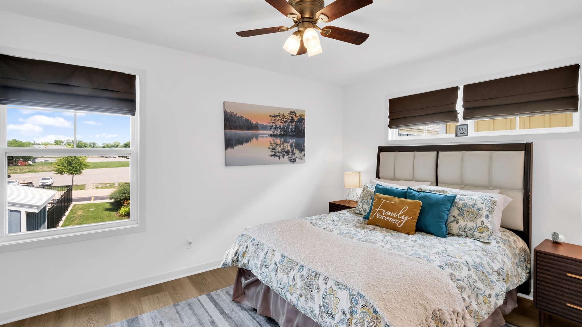 Unwind in your serene bedroom with lake artwork, plush bedding, and natural light streaming through windows.