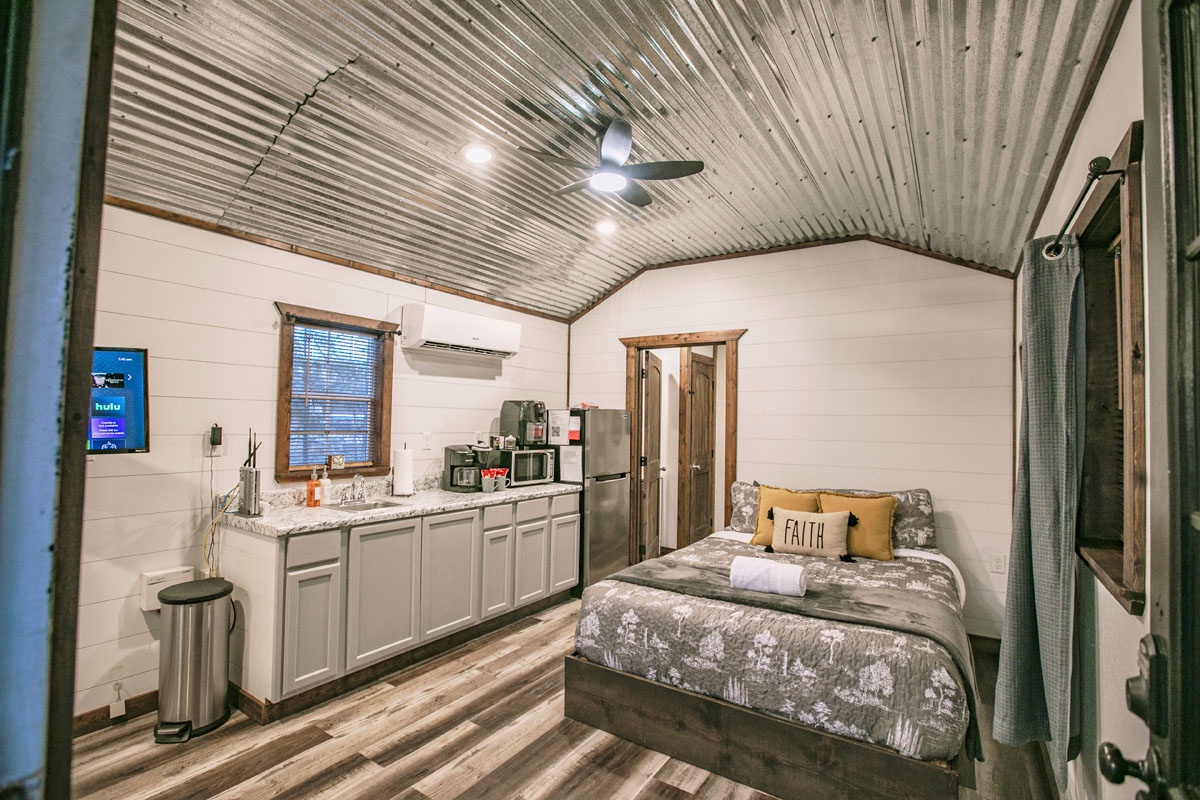 Relax in your charming studio featuring a cozy bed, full kitchen, and unique corrugated ceiling that adds character to your peaceful retreat.