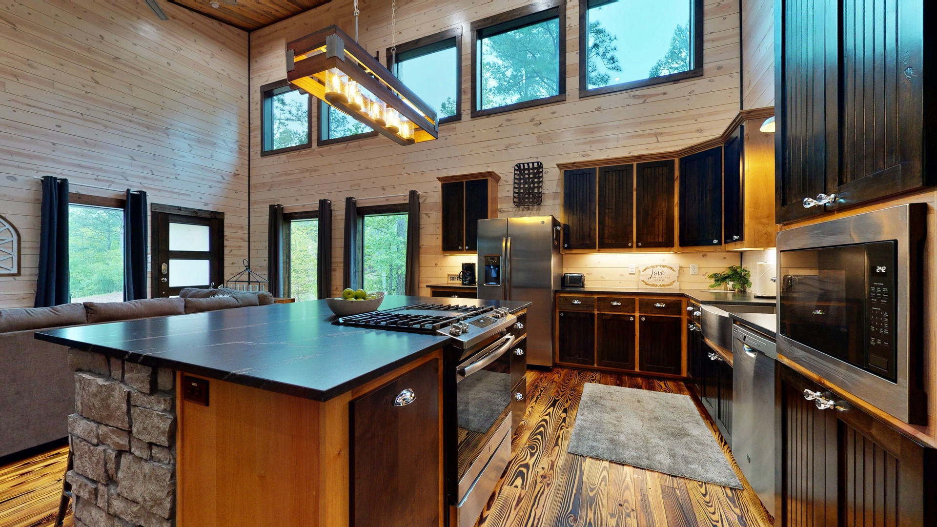 Your gourmet kitchen features stainless steel appliances, a spacious island with gas cooktop, and soaring wood-paneled ceilings with abundant natural light streaming through oversized windows.