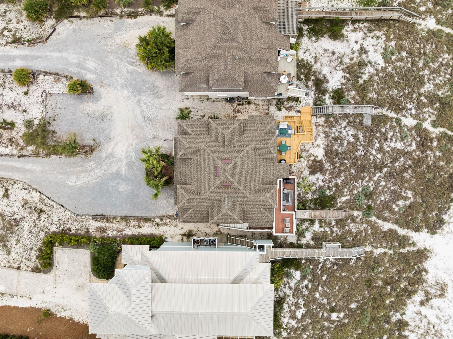 Aerial view of the property showcasing the main building, outdoor amenities, and the surrounding natural coastal landscape with sandy terrain and scattered vegetation.