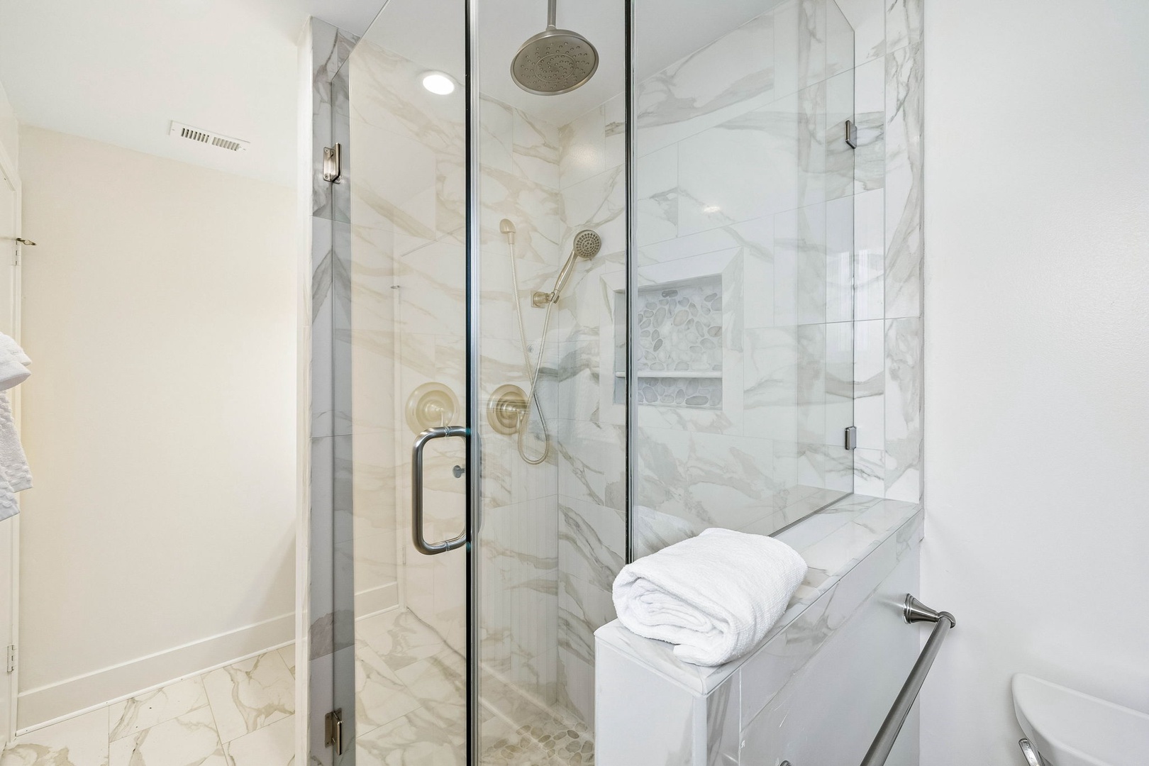 Step into your spa-like retreat with elegant marble-clad walls, rainfall shower, and plush towels waiting for you.
