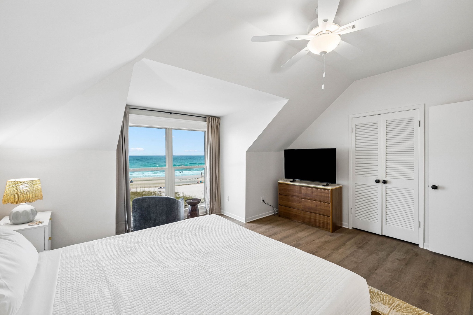 Wake up to stunning ocean views through the sliding glass door. Your private coastal retreat features a plush bed, modern TV, and charming vaulted ceilings with a ceiling fan to keep you comfortable.