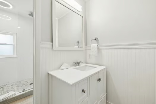 Fresh and bright, your private bathroom features a clean vanity, mirror, and a separate walk-in shower with elegant tile flooring—perfect for unwinding after a day of exploring.