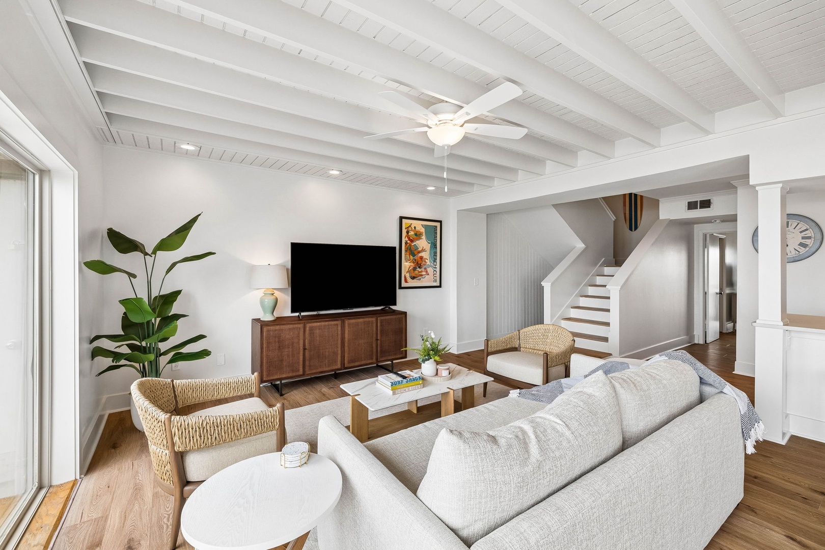Settle into this bright and airy living space where vaulted ceilings and natural textures create your perfect retreat. Unwind on plush seating as sunlight streams through large windows, warming the rich hardwood floors beneath your feet.