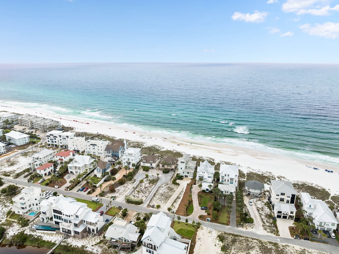 Aerial view of a pristine beachfront community along the Gulf Coast, featuring white-sand beaches and turquoise waters stretching to the horizon.