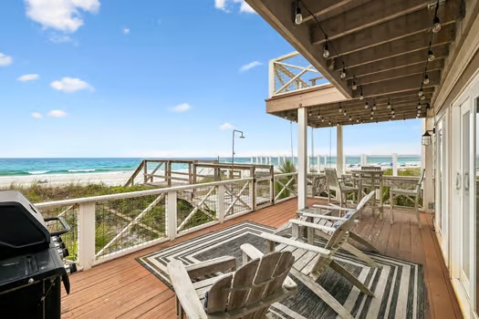 Spacious beachfront deck overlooks white sands and turquoise waters, offering a serene coastal retreat with comfortable lounge seating and easy beach access.