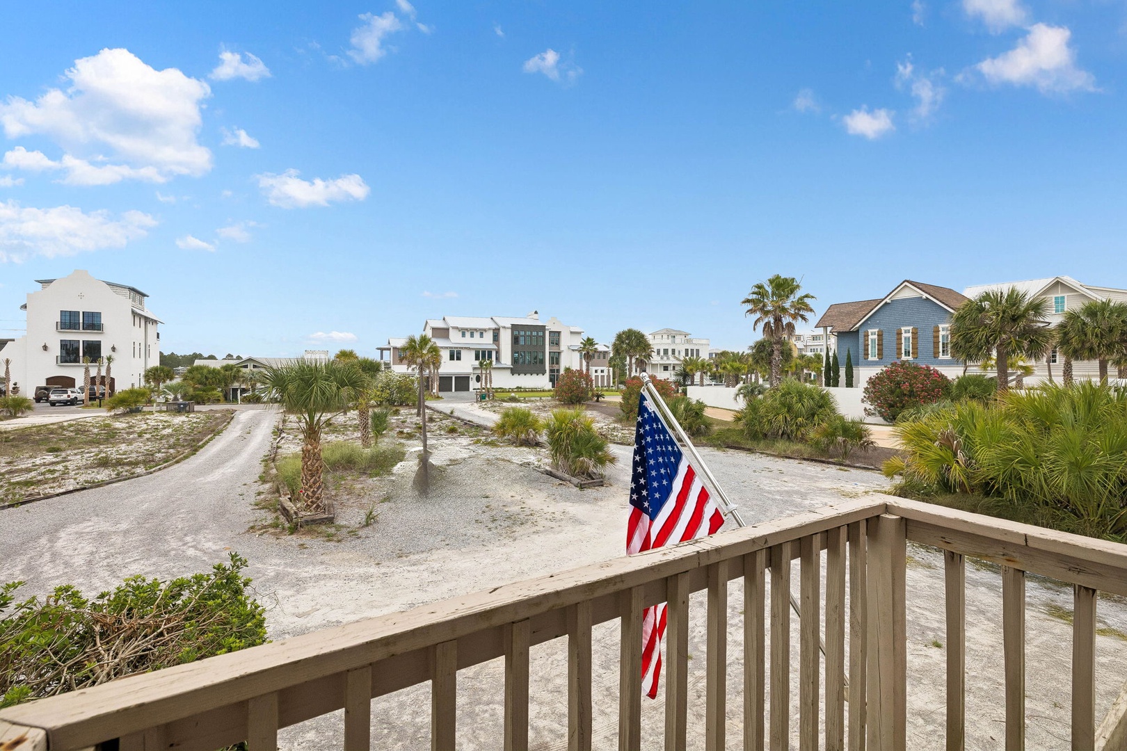 A coastal neighborhood featuring palm trees, sandy streets, and beach-style homes under a bright blue sky—the picturesque setting surrounding the property.