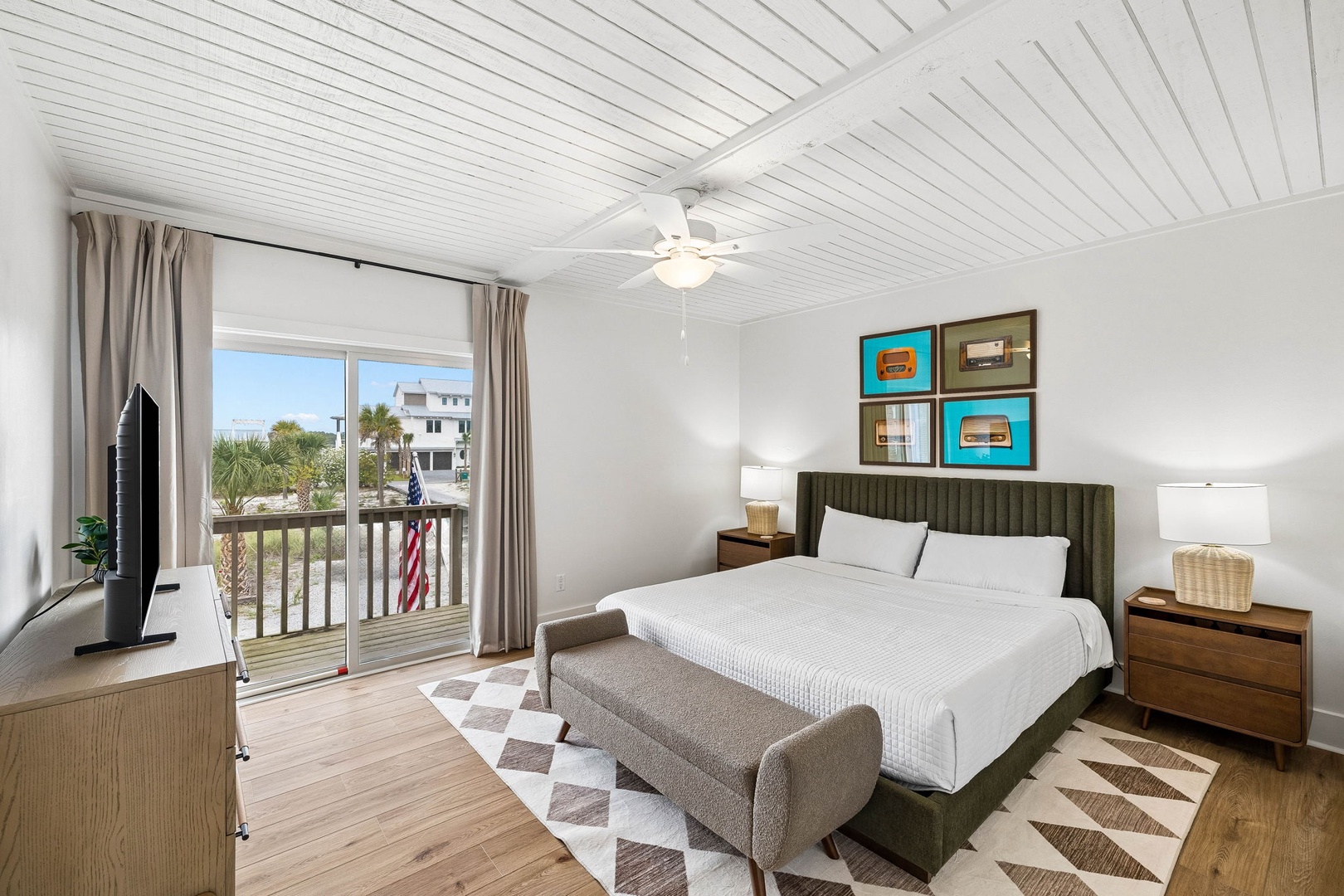 Your coastal bedroom features warm wood floors, crisp white linens, and a balcony overlooking palm trees—perfect for morning coffee or evening unwinding.