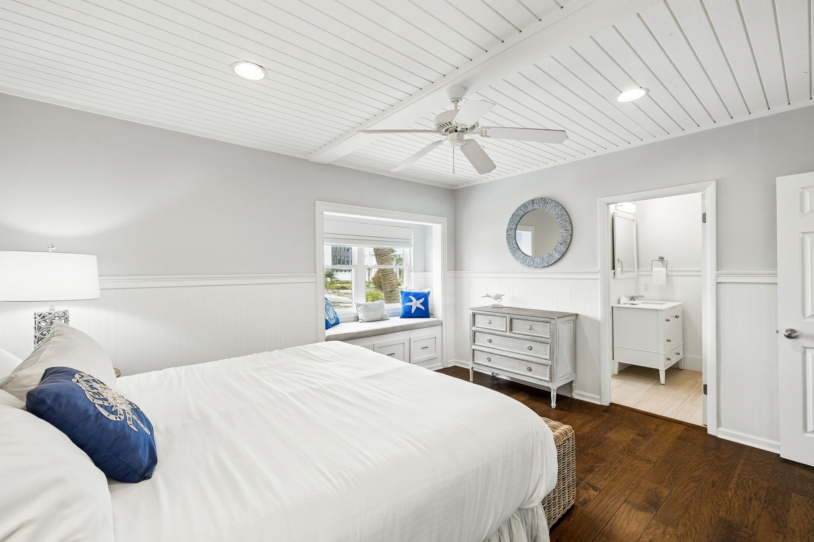 Relax in your serene bedroom featuring a cozy king bed, vaulted shiplap ceilings, and nautical touches. A peaceful window nook beckons for morning coffee, while your ensuite bathroom awaits just steps away.