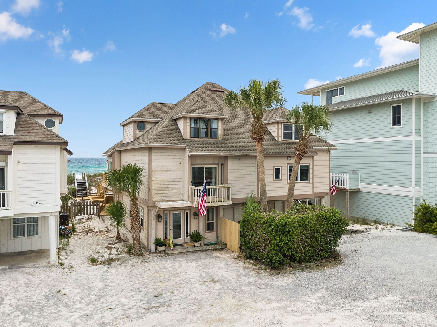 Beachfront property nestled among coastal homes with ocean views and palm trees, offering a quintessential seaside vacation setting just steps from the shore.