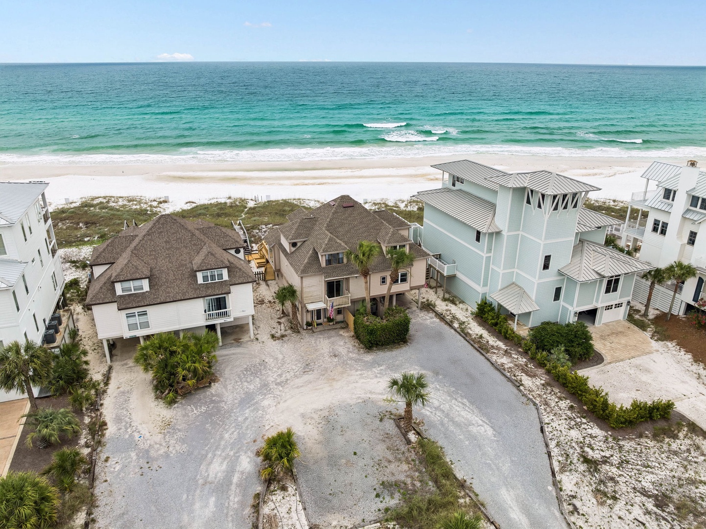 Beachfront properties nestled along pristine white sand and turquoise Gulf waters, offering a tranquil coastal setting surrounded by natural dunes and tropical landscaping.