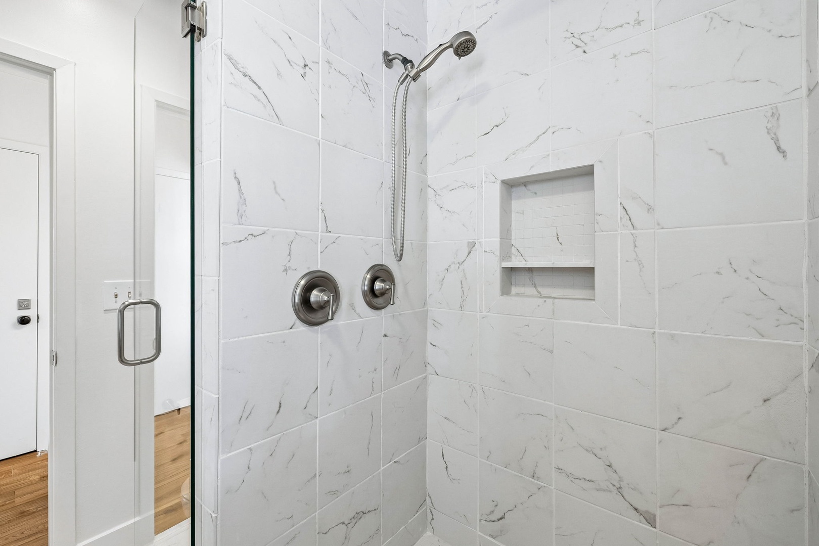 Sleek marble-look tile wraps your private shower, with dual controls and a handheld sprayer for your comfort. The built-in niche keeps your essentials within easy reach.