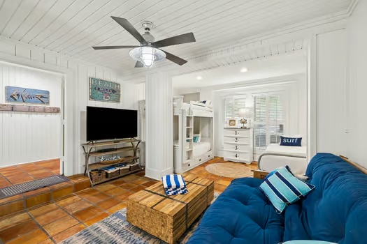 Sink into the plush blue sofa and unwind in your bright, coastal-chic living room. Warm wood floors, beachy accents, and a ceiling fan create your perfect vacation retreat.