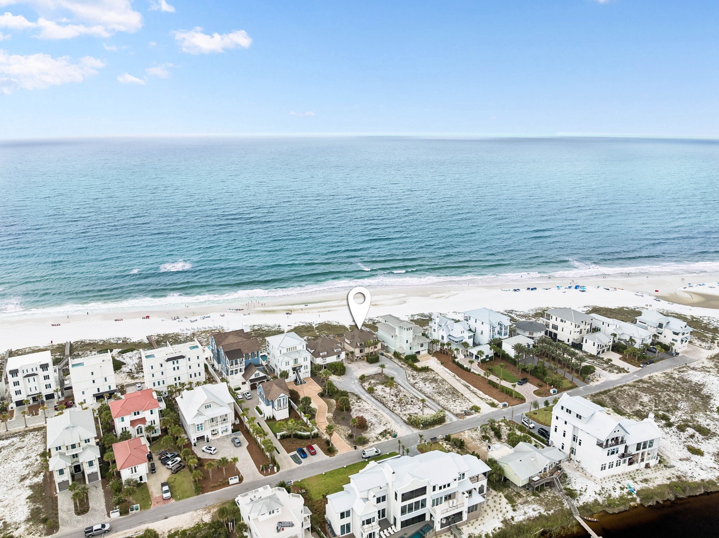 Aerial view of a beachfront vacation rental community nestled along pristine white sand shores, surrounded by turquoise Gulf waters and coastal dunes.