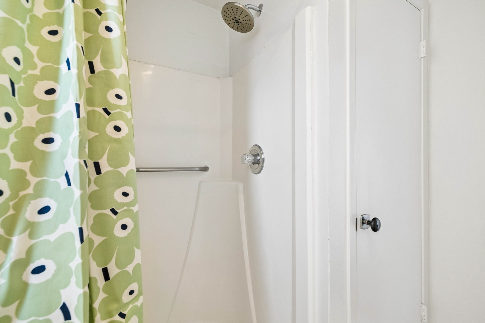 A bright, clean shower awaits, featuring a rainfall showerhead and cheerful floral curtain to brighten your morning routine and refresh you after a day of exploring.