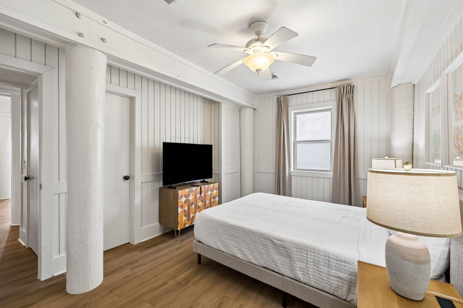 Step into your serene bedroom retreat with crisp white shiplap walls and warm wood floors. Sink into the plush bed after your beach day, enjoy your favorite shows, and drift off under the gentle ceiling fan.