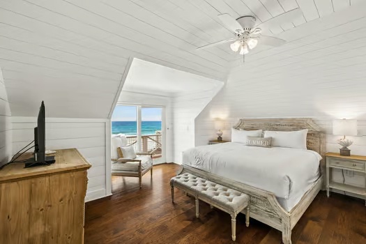 Wake up to stunning sea views from your plush king bed. White shiplap walls and hardwood floors create a serene coastal retreat, with French doors opening to your private balcony overlooking the ocean.